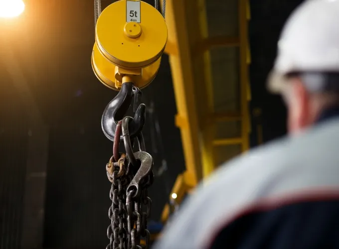 工場内でクレーンフックを用いた吊り作業を準備している